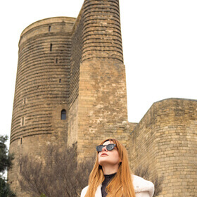 Woman posing in front of the Maiden Tower in Baku Old City during a photo tour
